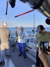An excited angler proudly displaying a catch aboard a fishing charter in open waters, surrounded by fellow fishermen.