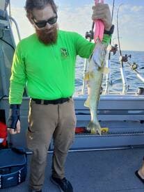 An angler proudly displaying a freshly caught Walleye while fishing on a boat, showcasing the excitement of a successful day on the water.