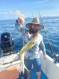 Angler proudly displaying a vibrant Mahi Mahi while fishing in open waters, showcasing a sunny day on the boat.