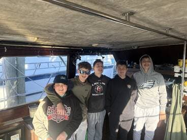 A group of young anglers enjoying their time inside the boat, showcasing camaraderie before heading out for a fishing adventure.