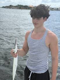 A young angler proudly displaying a Barracuda caught while fishing in a coastal waterway.