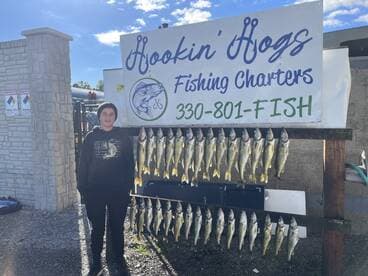 A young angler stands proudly next to a display of freshly caught Walleye at Hookin' Hogs Fishing Charters, showcasing a successful fishing trip.