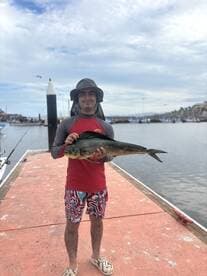 A young angler proudly displaying a Mahi Mahi on the dock after a successful fishing trip.
