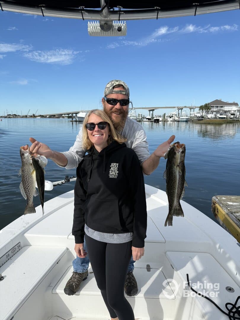 Two anglers proudly displaying their catch of speckled trout while enjoying a day on the water.