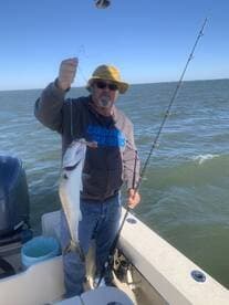 An angler proudly displaying a freshly caught fish while fishing on a boat, showcasing a sunny day on the water.
