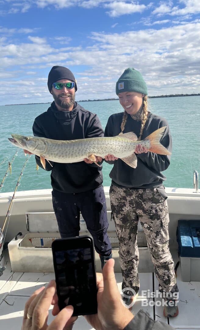 Two anglers proudly displaying a large Northern Pike on a fishing charter in clear waters, capturing a memorable moment.