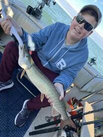 A young angler proudly displaying a caught fish while aboard a fishing boat, showcasing a successful day on the water.