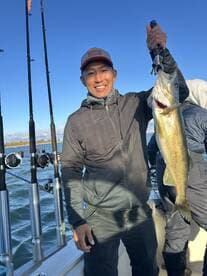 Angler proudly displaying a large Walleye while fishing on a boat, showcasing a beautiful day on the water.