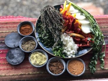 A vibrant display of fresh vegetables and spices arranged on a plate, showcasing ingredients likely for a seafood dish.