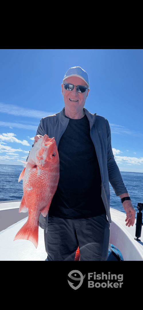 An angler proudly displaying a vibrant Red Snapper while fishing offshore, showcasing a successful day on the water.