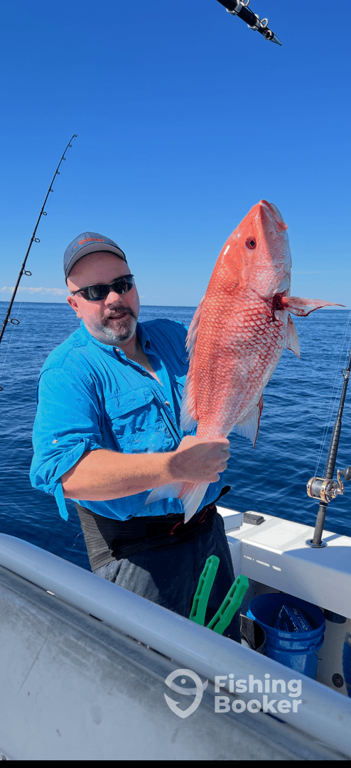 An angler proudly displaying a large Red Snapper while fishing offshore, showcasing a successful day on the water.