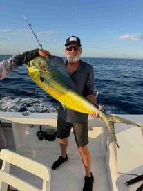 An angler proudly displaying a vibrant Mahi Mahi while fishing offshore, showcasing the excitement of a successful catch.