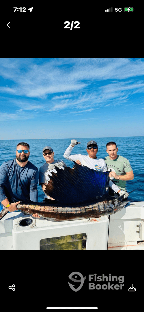 Group of anglers proudly displaying a large Sailfish aboard their boat during a deep-sea fishing trip.