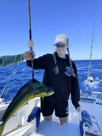 A young angler proudly displaying a vibrant Mahi Mahi while fishing offshore, showcasing the excitement of a successful catch.