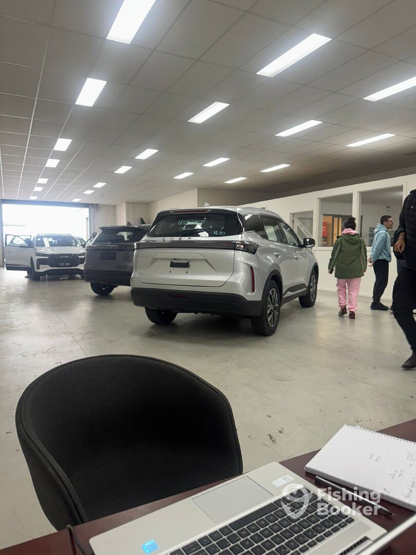 An indoor setting with several vehicles visible, likely in a car dealership, featuring a mix of adults and children.