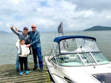 A family proudly displays their catch of the day, showcasing a couple of fish while enjoying a fishing trip on a scenic waterway.