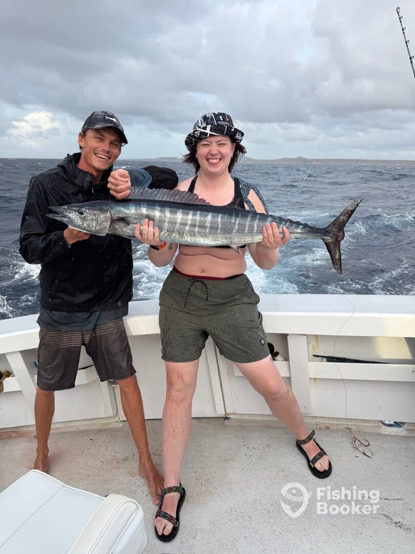Two anglers celebrating a successful catch of a Wahoo while fishing offshore, showcasing the excitement of deep-sea fishing.