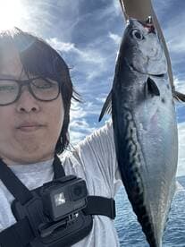 Angler proudly displaying a large fish against a scenic ocean backdrop while fishing on a sunny day.