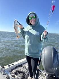 Angler proudly displaying a caught Speckled Trout while fishing on a sunny day.