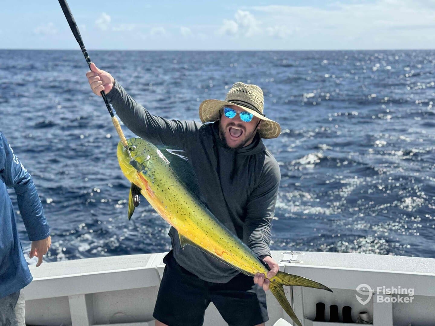 An excited angler proudly displaying a vibrant Mahi Mahi while fishing offshore, showcasing the thrill of deep-sea fishing.