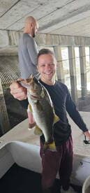 Angler proudly displaying a large Largemouth Bass while fishing under a bridge, showcasing a successful day on the water.