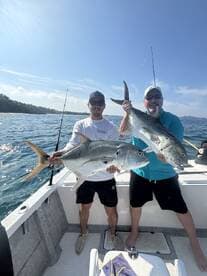 Two anglers proudly displaying their catches of large fish while out on the water, showcasing a successful day of fishing.