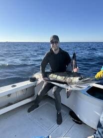 An angler proudly displaying a large Mahi Mahi on a fishing boat, showcasing a successful offshore fishing trip.