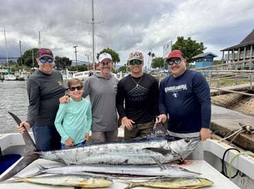 A family group proudly displays their catch, including a large Marlin and a Mahi Mahi, at the dock after a successful fishing trip.