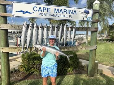 An angler proudly displaying a large Barracuda in front of a catch board at Cape Marina, Port Canaveral, FL.