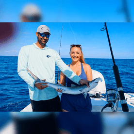 Anglers proudly displaying a caught shark while enjoying a sunny day on the open ocean.