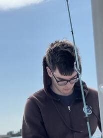 A young angler focused on fishing while preparing his rod on a sunny day, showcasing the excitement of the fishing experience.
