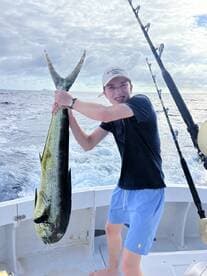 A young angler proudly displaying a large Mahi-Mahi while fishing offshore, showcasing the excitement of a successful catch.