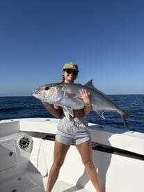 A young angler proudly displaying a large fish while on a fishing charter in open waters.