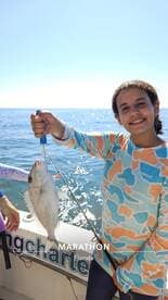 A young angler proudly displaying a Snapper while fishing off the coast of Marathon, Florida.
