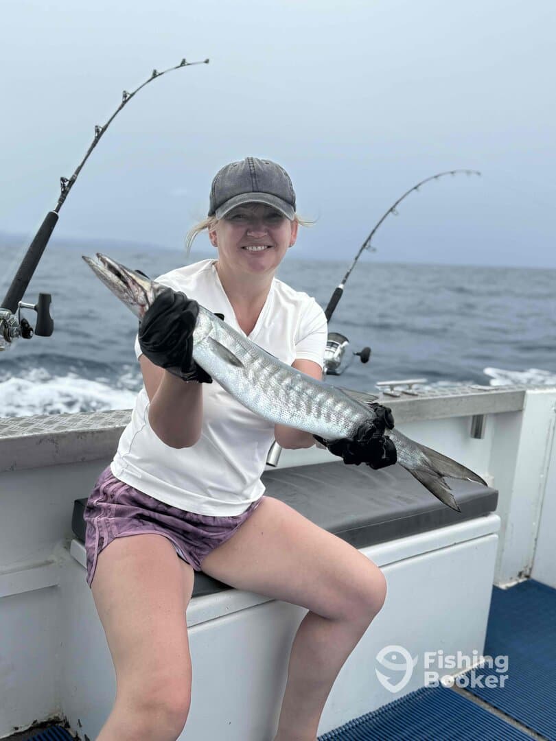 Angler proudly displaying a Barracuda while fishing on a charter boat, showcasing a successful day on the water.