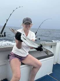 Angler proudly displaying a Barracuda while fishing on a charter boat, showcasing a successful day on the water.