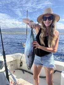 A proud angler displaying a large Tuna on a fishing boat, showcasing the thrill of deep-sea fishing.