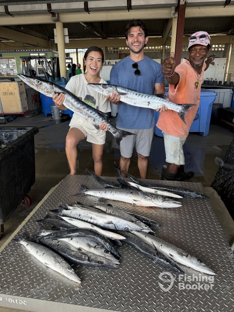 A group of anglers proudly displaying their catch of Barracuda after a successful fishing trip at the dock.