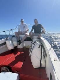 Two anglers relaxing on the deck of a fishing boat, enjoying a sunny day on the water.