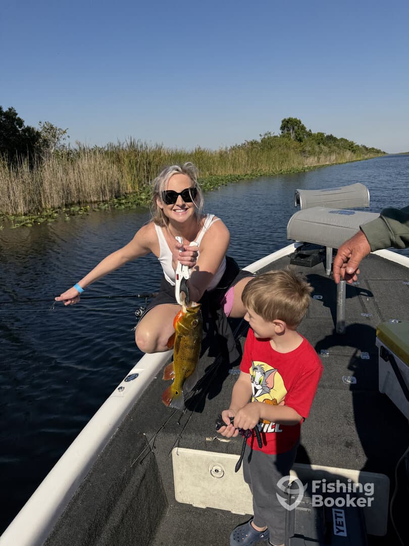 A young boy watches as an adult angler proudly displays a vibrant Yellow Perch while fishing on a scenic waterway.