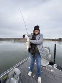 Angler proudly displaying a freshly caught fish while fishing on a calm lake, showcasing a cozy winter fishing experience.