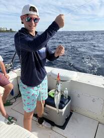 A young angler proudly displaying a caught fish while fishing on a boat, showcasing a vibrant fishing environment.