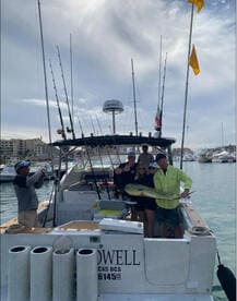 A group of anglers proudly displaying a large Mahi Mahi aboard a sportfishing boat in a marina setting.