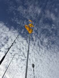 A view of fishing flags and rods against a cloudy sky, capturing the atmosphere of a fishing trip.