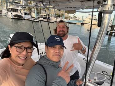 A cheerful group of anglers posing inside the boat, ready for a fishing adventure in a marina setting.