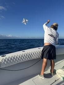 An angler casting a kite into the ocean while fishing from a well-equipped boat, showcasing an exciting fishing technique.