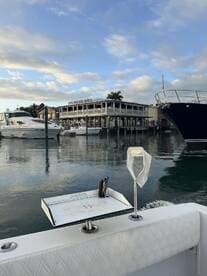 A scenic view of a marina featuring multiple boats and the iconic A&B Lobster House in the background, showcasing a well-equipped fishing boat with a cleaning station.