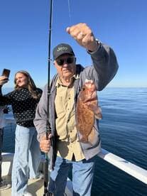 An angler proudly displaying a freshly caught fish while enjoying a day out on the water with family.