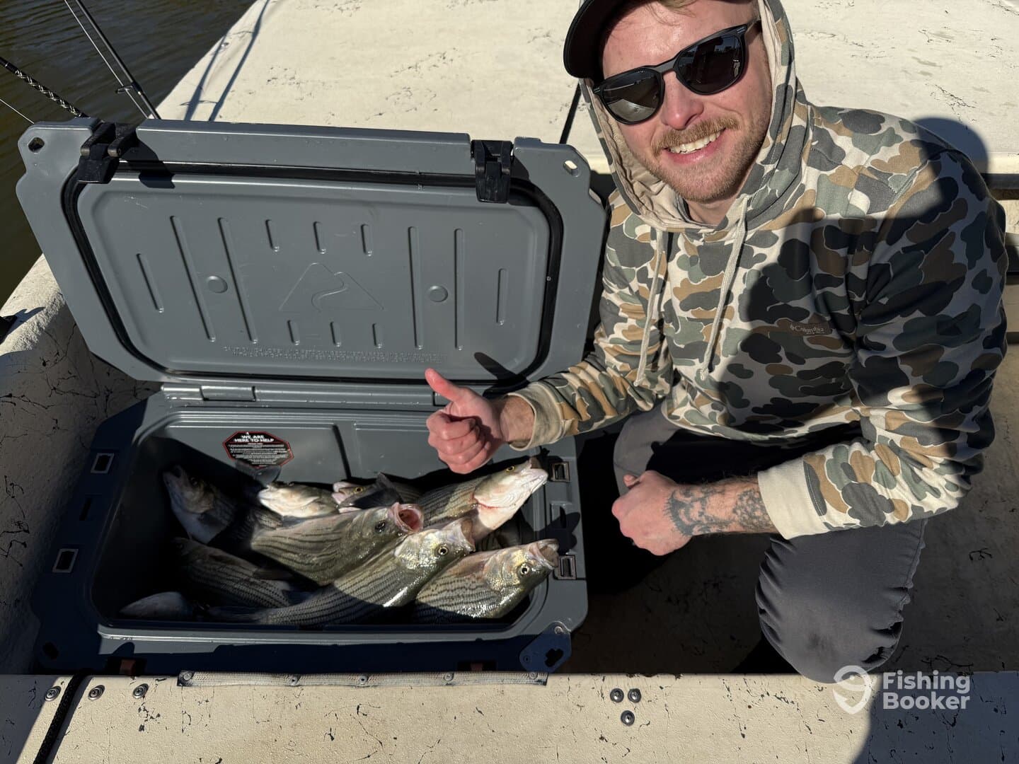 Angler displaying a cooler filled with several striped bass while enjoying a day on the water.