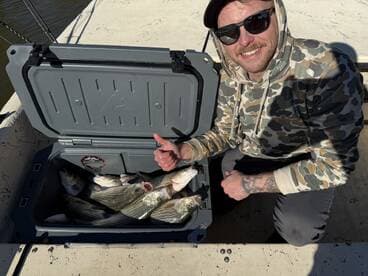 Angler displaying a cooler filled with several striped bass while enjoying a day on the water.